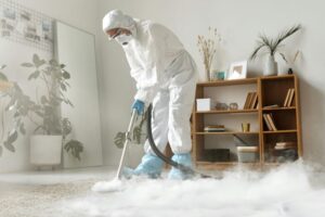 : A professional carpet cleaner in protective gear using steam cleaning equipment to deep clean a carpet in a modern living room.